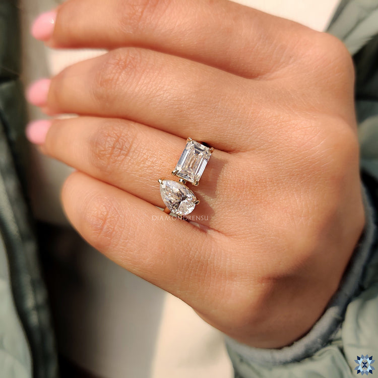 Beautiful simple engagement ring featuring a emerald cut moissanite and pear cut moissanite.
