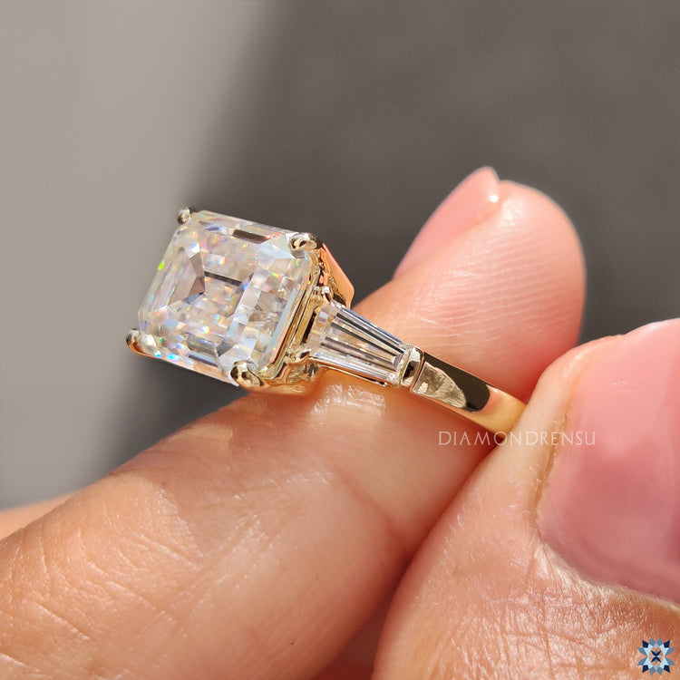 Moissanite engagement ring with three stones, including tapered baguette side stones.
