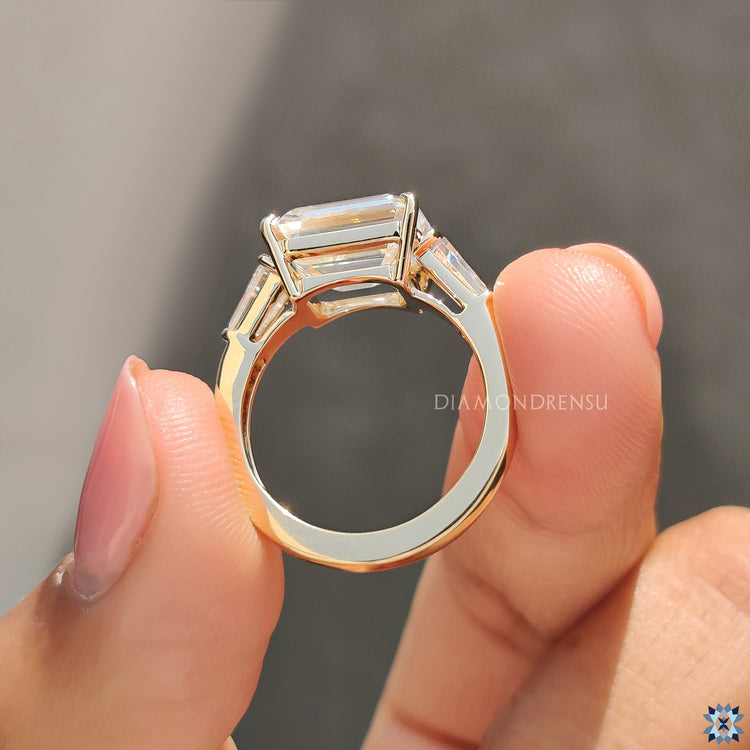 East to west ring setting with emerald cut moissanite and yellow gold accents.
