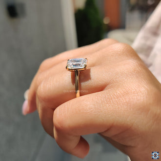 Simple solitaire engagement ring featuring an emerald cut stone, designed to highlight its natural brilliance.
