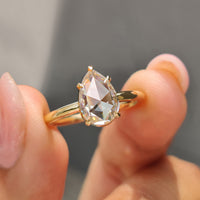 Yellow gold solitaire engagement ring featuring a pear rose cut diamond.
