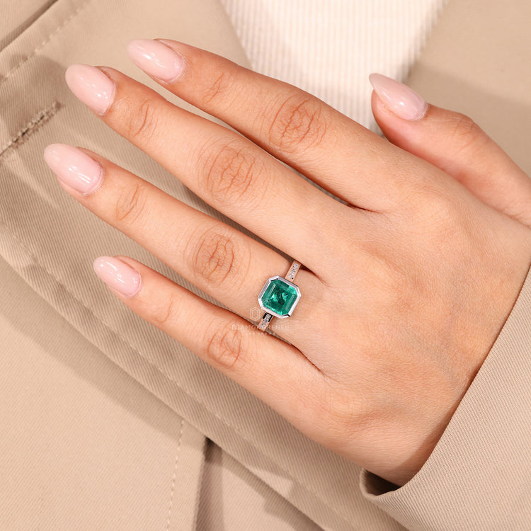 Channel setting ring with emerald center stone.
