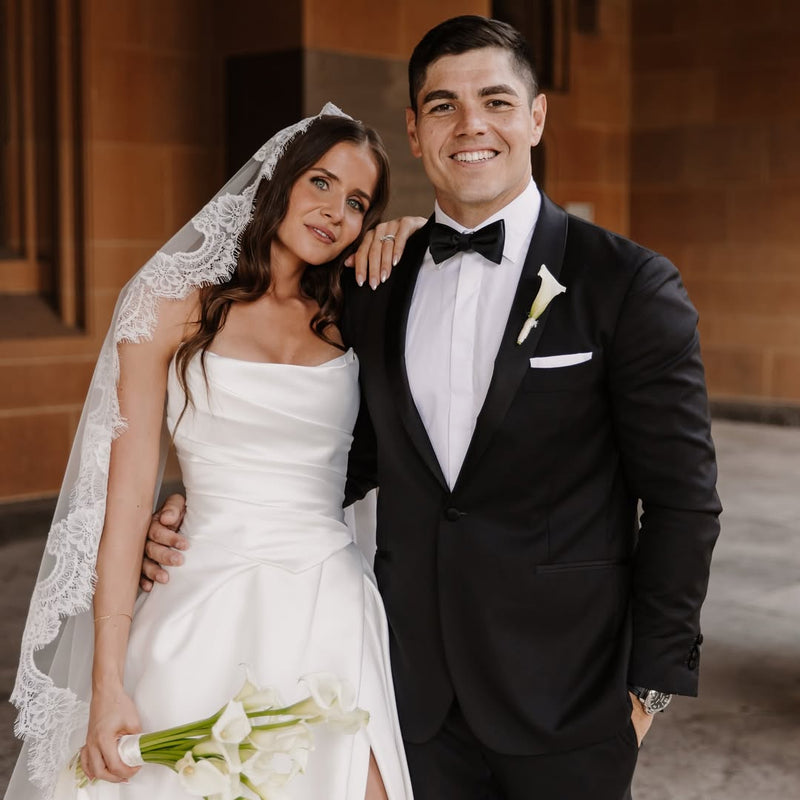 Classic lace bridal gown and black tuxedo wedding attire