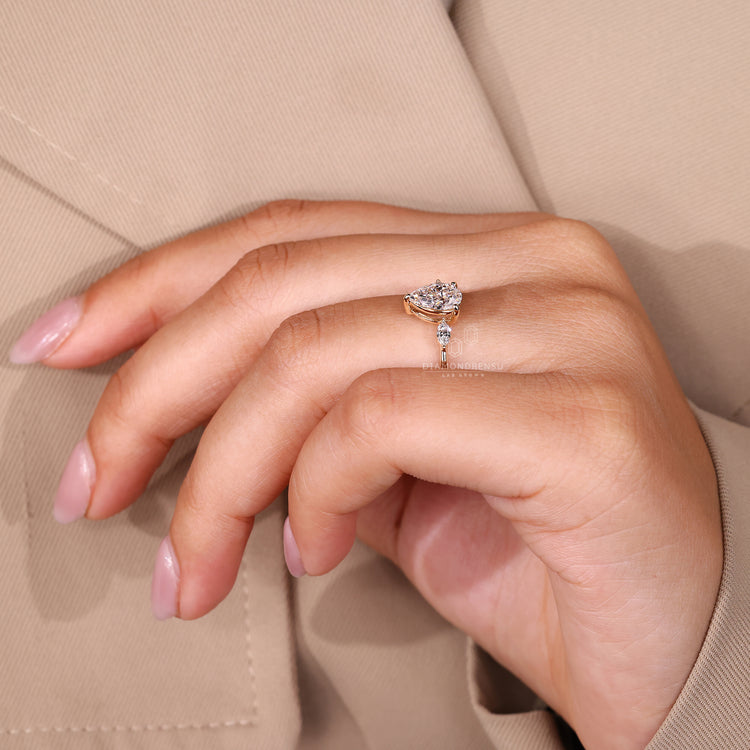 Yellow gold ring with three stone pear center diamond and prong setting.
