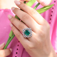 Emerald gemstone ring with halo design.

