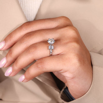 Designer engagement ring featuring emerald and round side diamonds
