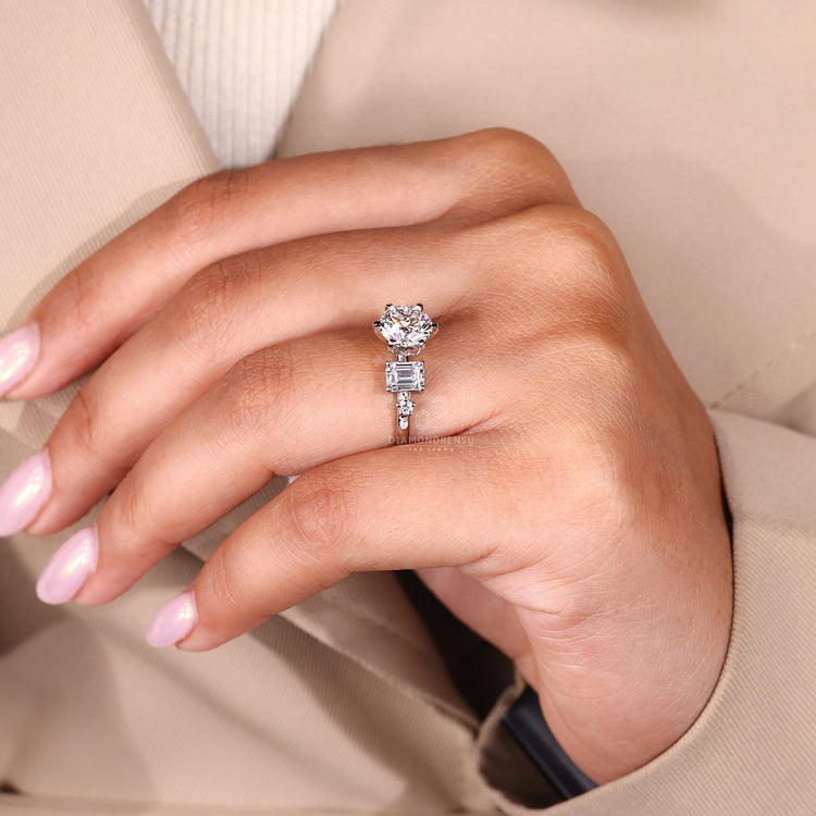 Designer engagement ring featuring emerald and round side diamonds
