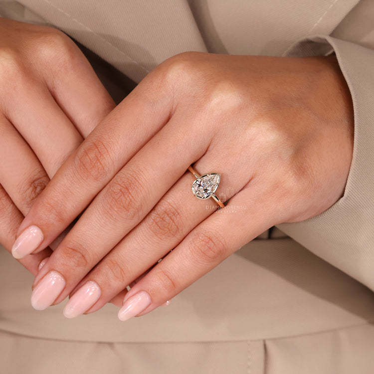 Pear cut diamond engagement ring with bezel type prong setting.
