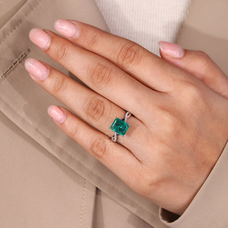 Twisted shank ring with emerald birthstone and custom diamond accents.
