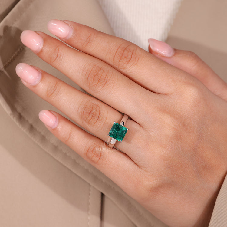 Asscher cut emerald ring in cathedral setting design.
