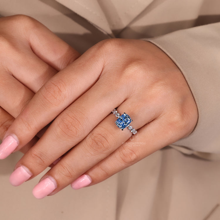 Diamondrensu ring featuring blue diamond cushion cut and 4 prong setting.
