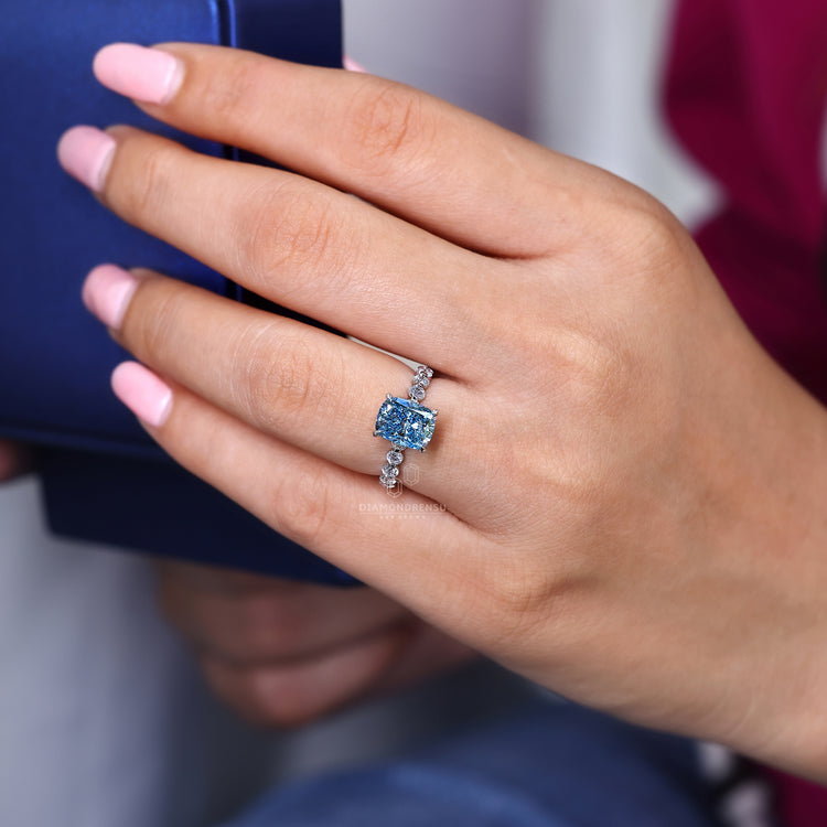 Blue cushion cut ring with shared prong design and white gold.

