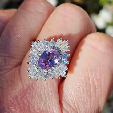 Purple gemstone halo ring shown on a finger