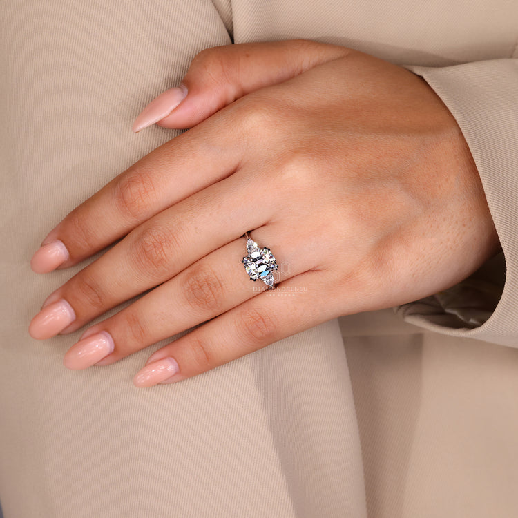 Cushion old mine diamond with pear side stones and claw prong detail.