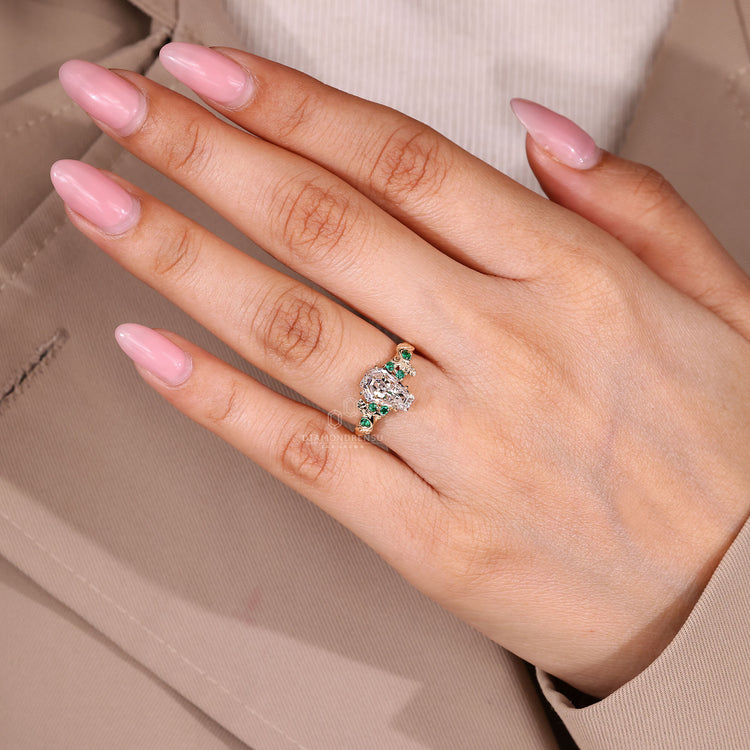 Coffin center stone ring with green emerald side details.
