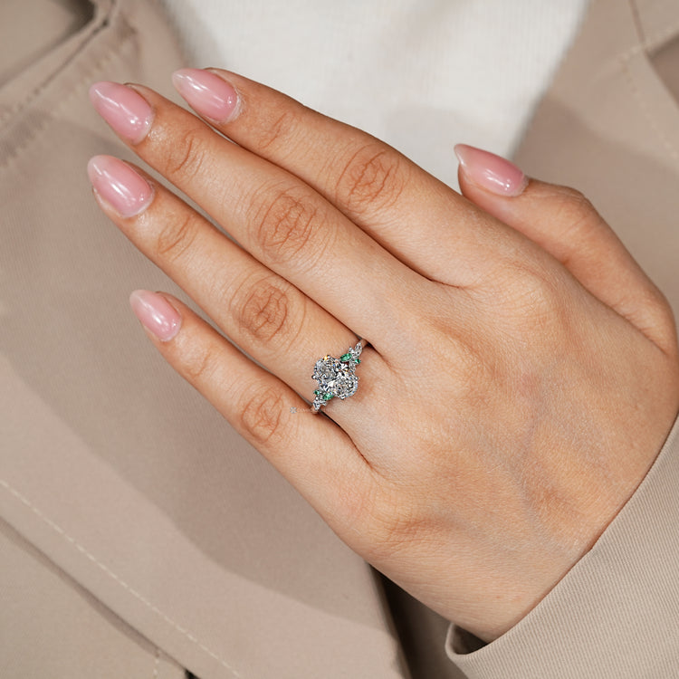 Oval engagement ring with round and marquise green emerald side stones.