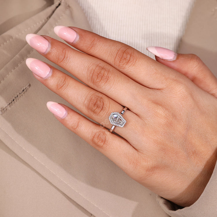 Coffin center stone ring with round halo diamond accents.