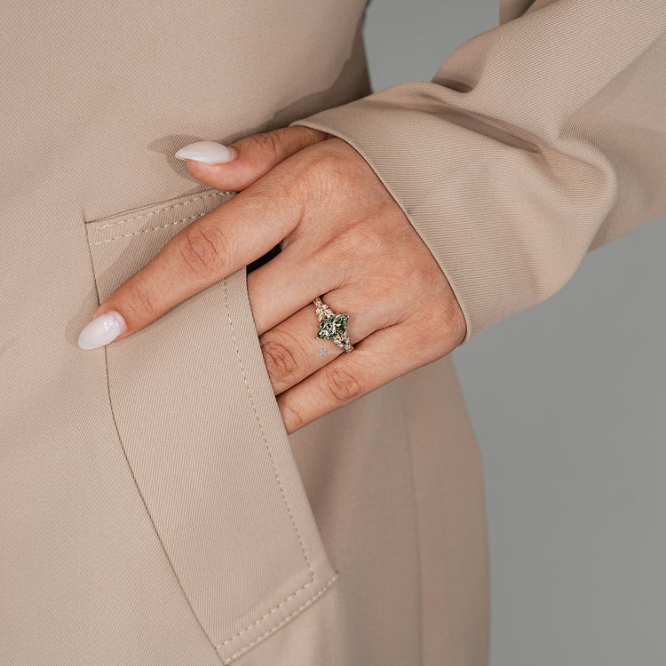 Marquise ring with a tulip setting over a green center stone.