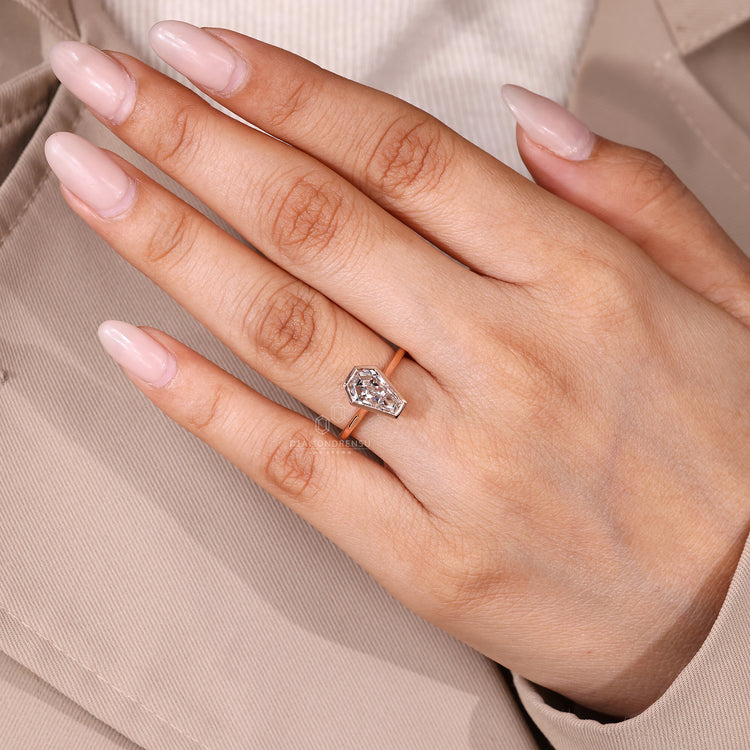 Coffin cut engagement ring with bezel setting and cathedral structure.