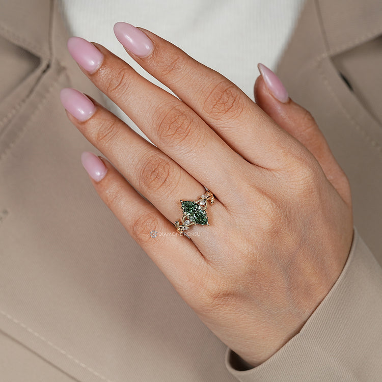 Six claw prong setting holds the green marquise center stone.