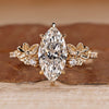 Marquise cut engagement ring with flower design and side stones.