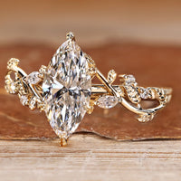 Nature inspired engagement ring with marquise center stone and side accents.
