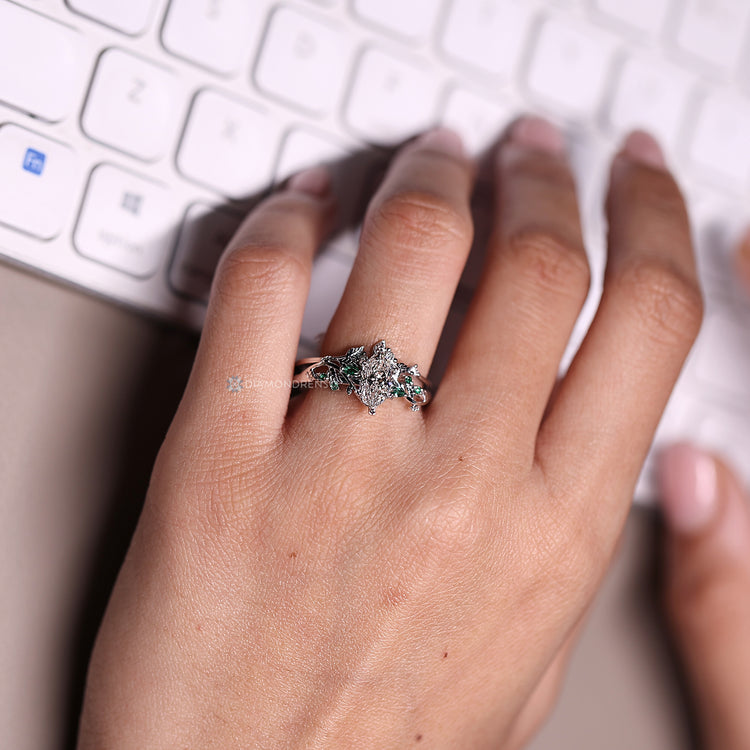 Marquise and round cut emerald gemstone complement the center stone.
