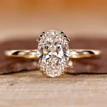 Solitaire engagement ring with oval cut diamond and triple prong setting.
