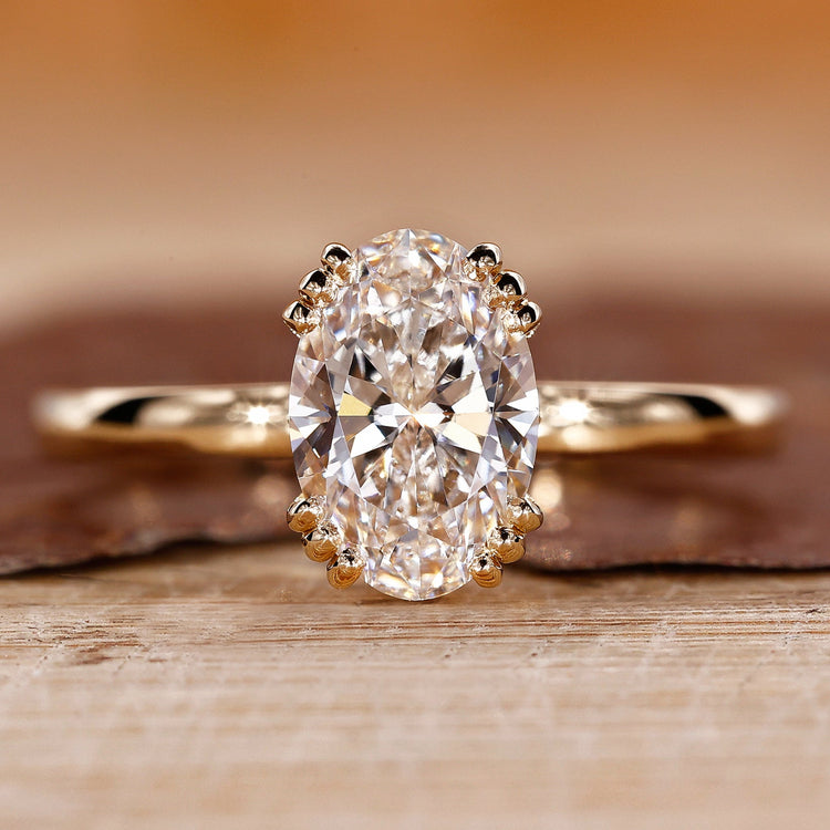 Solitaire engagement ring with oval cut diamond and triple prong setting.