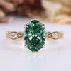 Oval cut diamond ring with green center stone and round side stones.
