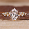 Oval diamond ring with cluster setting and round stones.