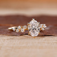 Oval diamond ring with round side stones in cluster.