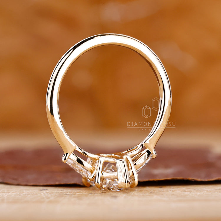 Diamondrensu ring with Dutch marquise ring, three stone engagement ring, and four claw prong in yellow gold.
