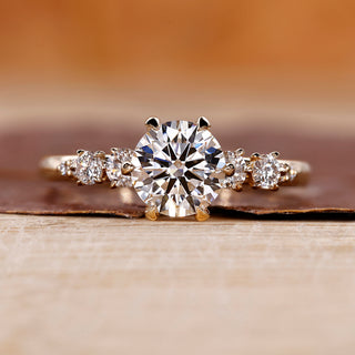 Side Stone Engagement Ring with round cut diamonds in a six claw prong setting.
