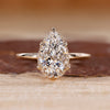 Pear cut diamond ring featuring hidden halo design and leaf style prong setting.
