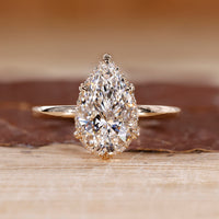 Pear cut diamond ring featuring hidden halo design and leaf style prong setting.

