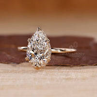 Solitaire diamond ring with pear cut center and leaf inspired prongs.
