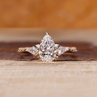 Pear cut engagement ring with three stone design and kite side stone.
