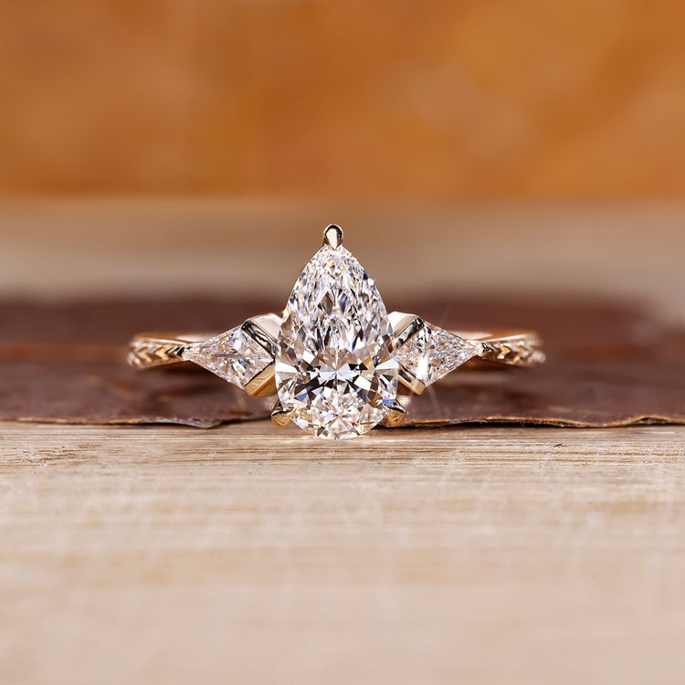 Pear cut engagement ring with three stone design and kite side stone.
