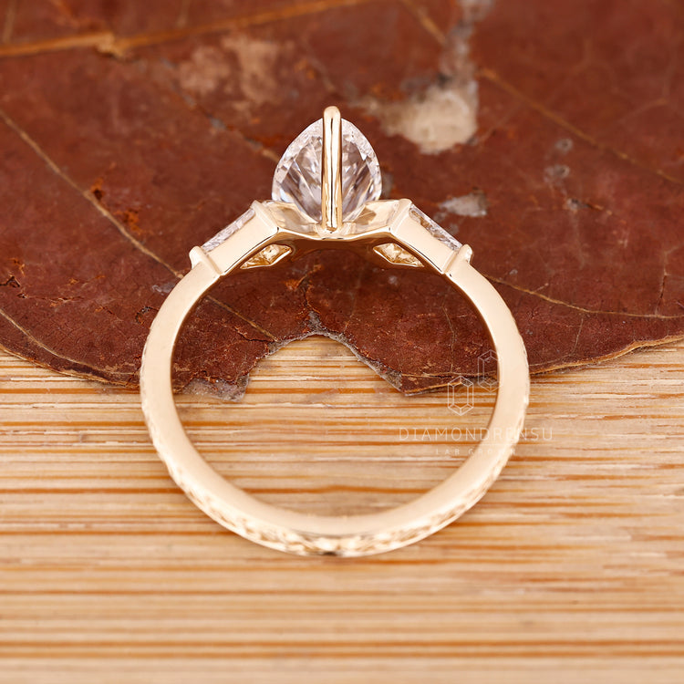 Art deco pear cut engagement ring with three stone kite side stone.
