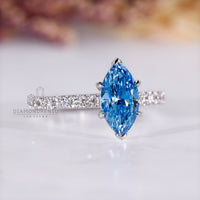 Cathedral setting ring holding blue marquise diamond securely in white gold.
