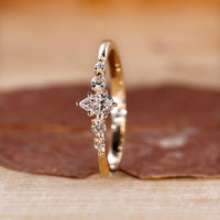 Shared prong engagement ring in yellow gold with round cut side stones.
