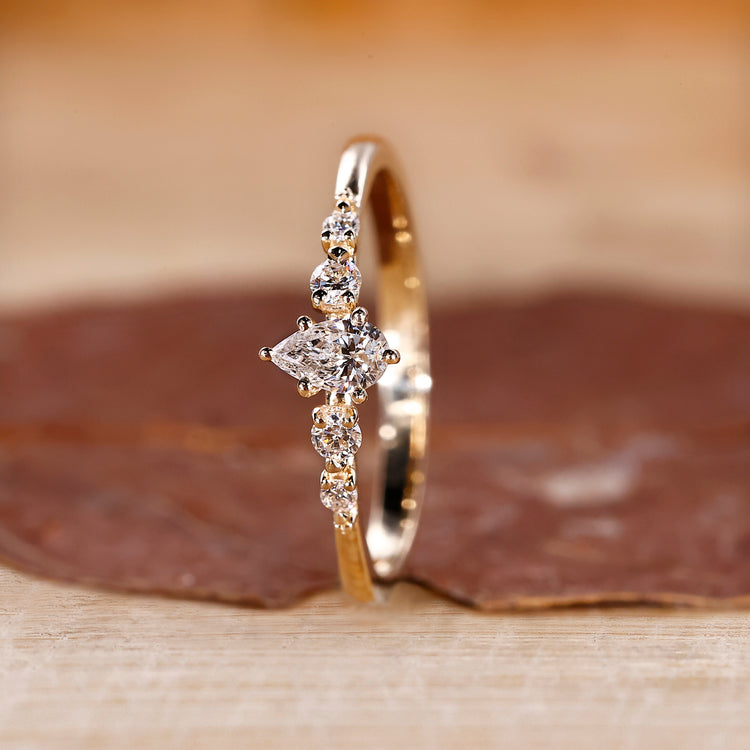 Shared prong engagement ring in yellow gold with round cut side stones.
