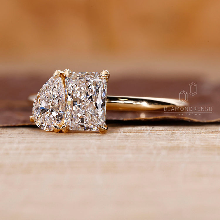 2 stone diamond ring with radiant and pear cut diamonds in yellow gold.

