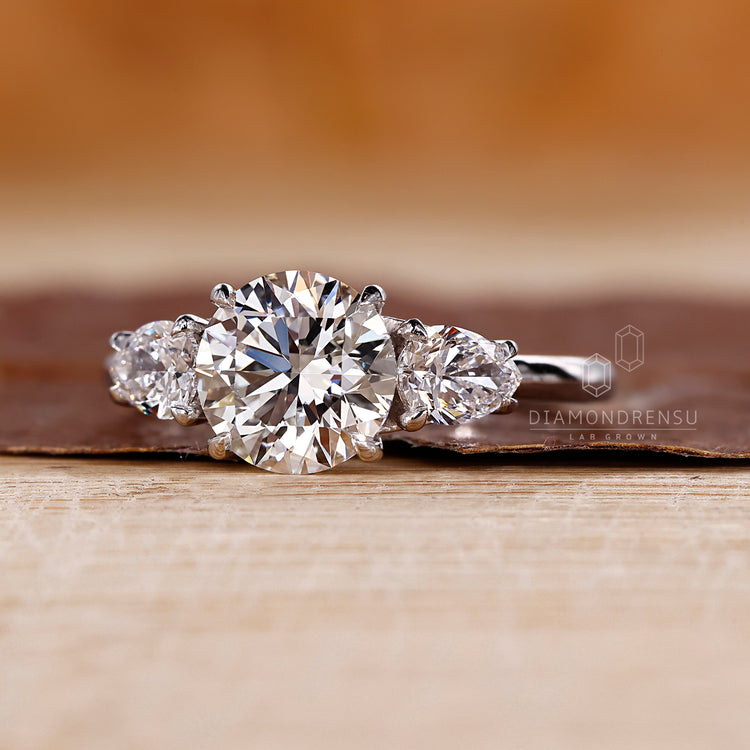 Custom engagement ring with 4 claw prong setting and pear side stones.
