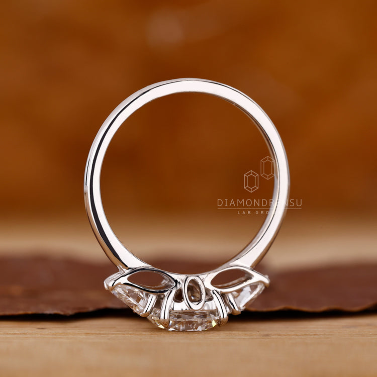 Diamondrensu engagement ring with round center stone and pear side stones.
