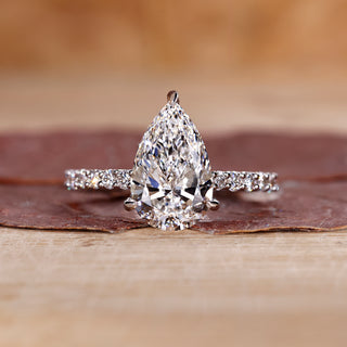 Pear shaped diamond ring with pave band in white gold.
