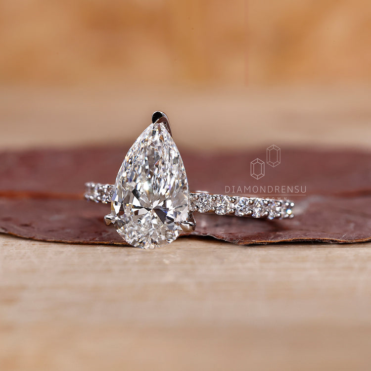 Pave round cut band with pear shaped diamond centerpiece.
