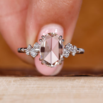 Oval rose cut diamond ring with cluster diamond design in white gold.
