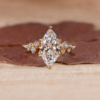 Marquise cut engagement ring with round cut side stones in a diamond ring design with a cluster setting.
